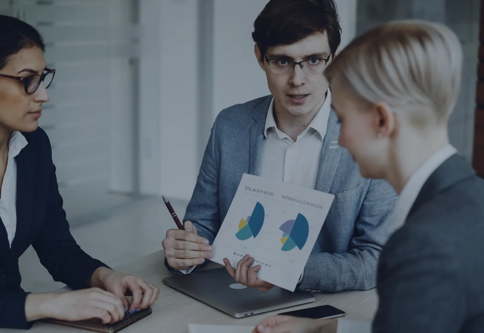 Three colleagues discussing a printed document at a desk