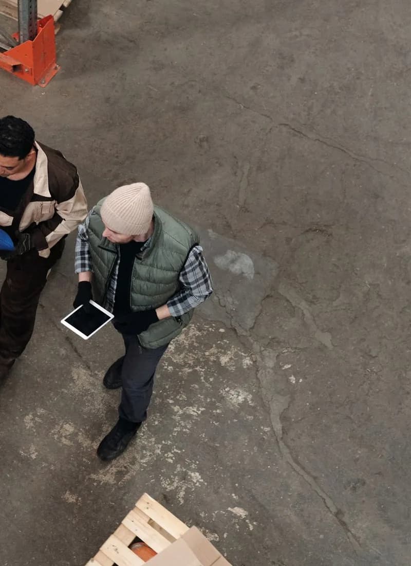 Two warehouse workers with a tablet, seen from above